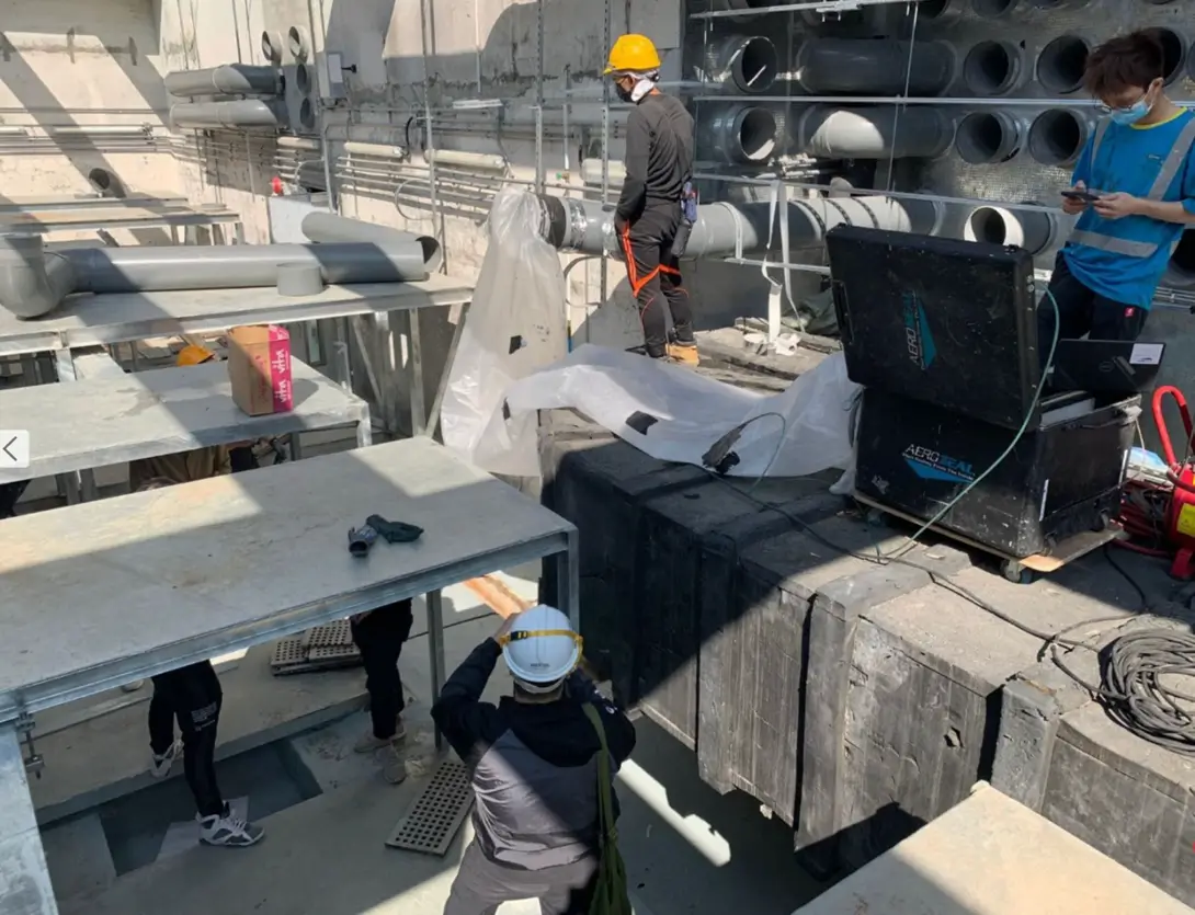 Technicians performing Aeroseal duct sealing on commercial rooftop ductwork for Reducing HVAC energy costs